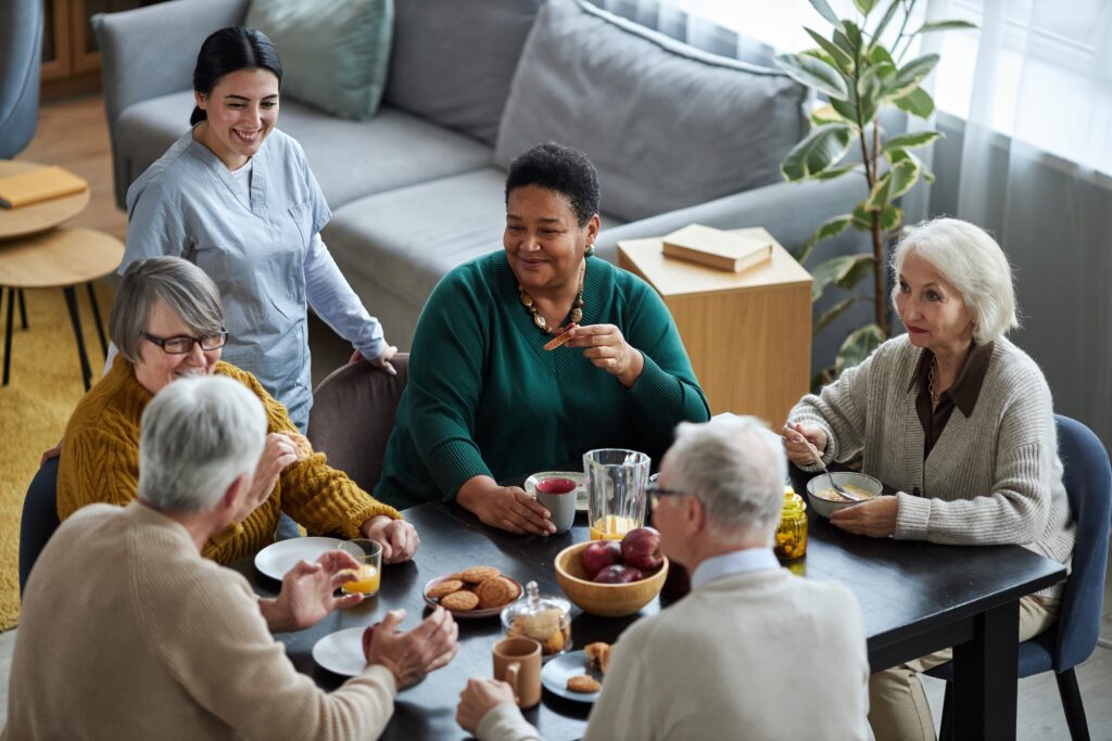 A group of seniors sit around a table sharing food.